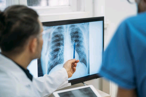 Radiographer and healthcare worker examining a chest X-ray in a diagnostic imaging facility